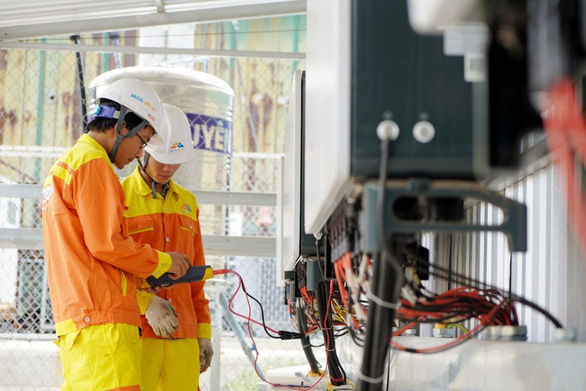 Technician inspecting solar inverter and wiring during a maintenance check