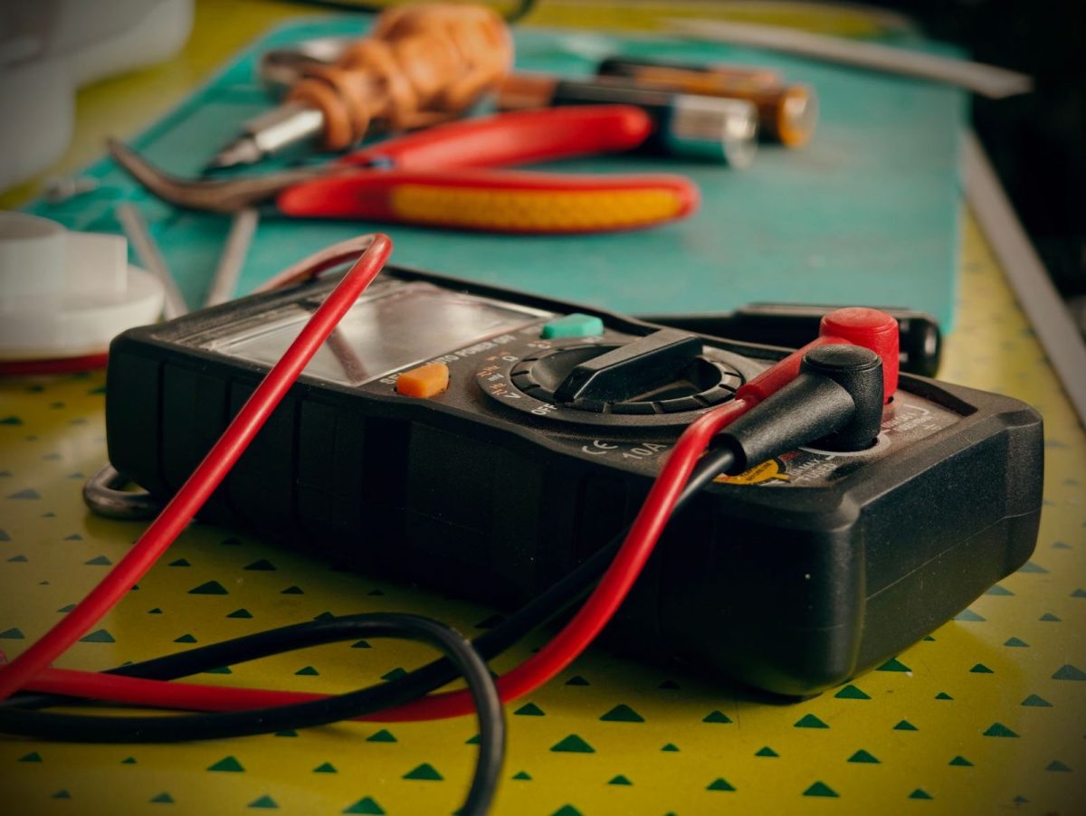 Technician measuring solar system voltage with a multimeter during a fault check