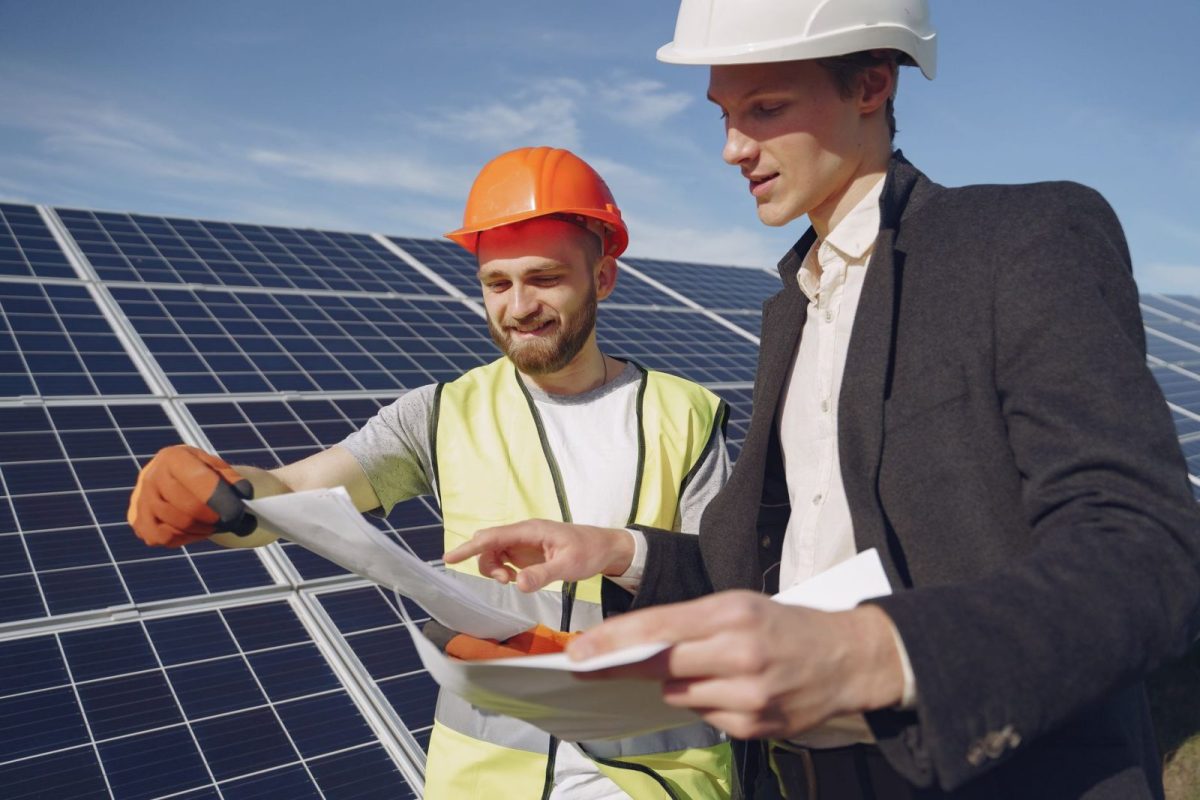 Engineer inspecting rows of solar panels in a field